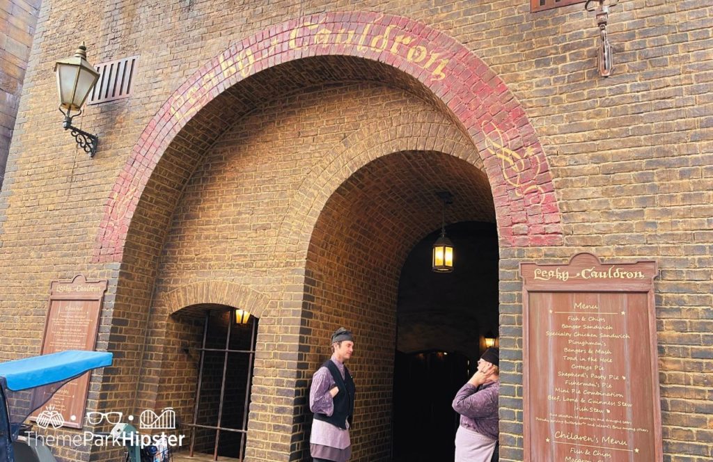 Universal Orlando Resort Leaky Cauldron entrance at Universal Studios Diagon Alley Harry Potter World with 2 staff standing out front by the menu. Keep reading to learn all the best things to do on a Universal Studios solo trip. 