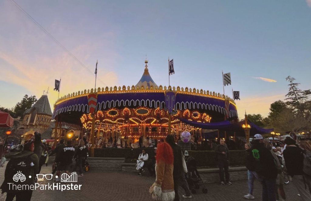 Disneyland Resort Fantasyland carousel lit up against the sunset and theme park guests walking by. Keep reading to find out more about the best food at Disneyland.