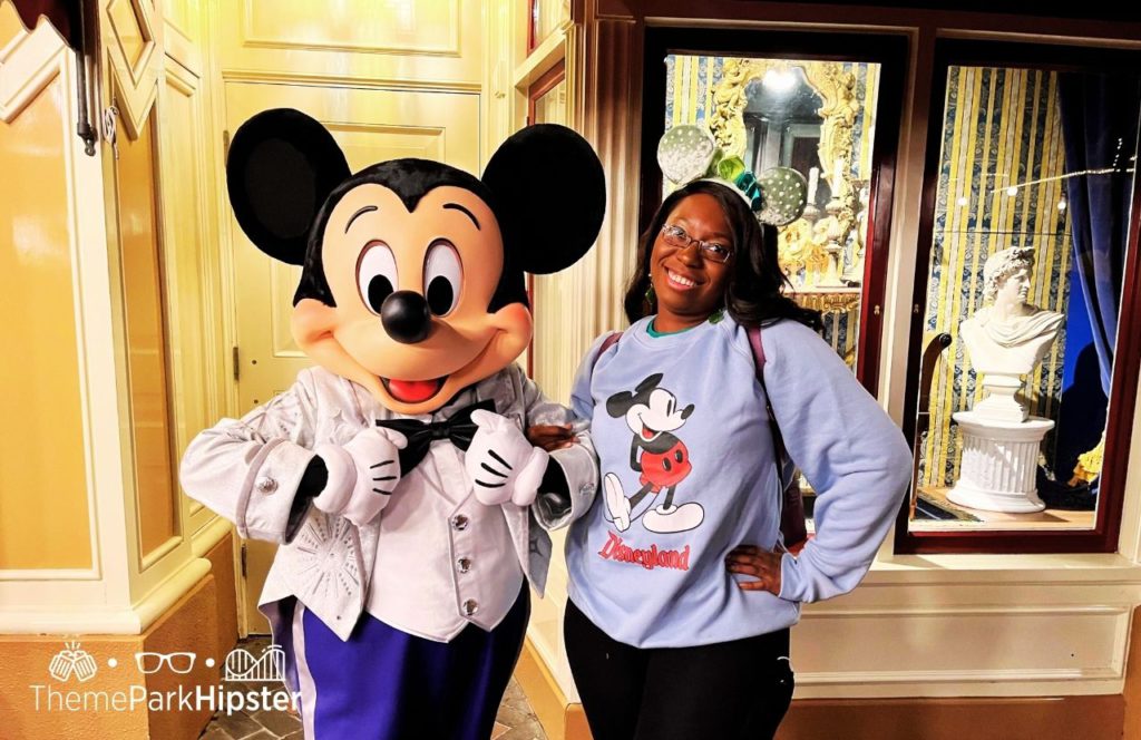 Disneyland Resort Mickey Mouse in Disney 100 Anniversary Outfit next to Victoria Wade. Keep reading about Mickey and Minnie's Runaway Railway at Disneyland vs Disney World.