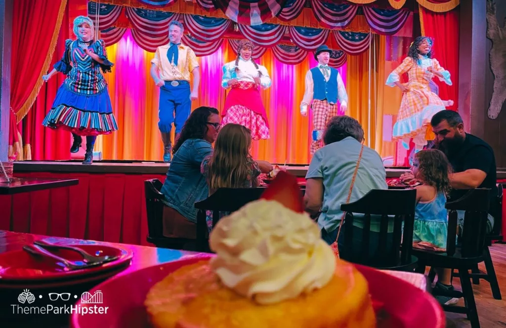 Dining on strawberry shortcake while watching the performers on stage at Disney Wilderness Lodge Resort Hoop Dee Doo Musical Revue. Keep reading to learn more of the best things to do at Disney World for solo travelers. 