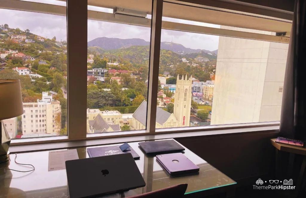 Loews Hollywood Hotel Near Universal Studios Hollywood King Bedroom Suite view of Hollywood Sign with Laptop on table.