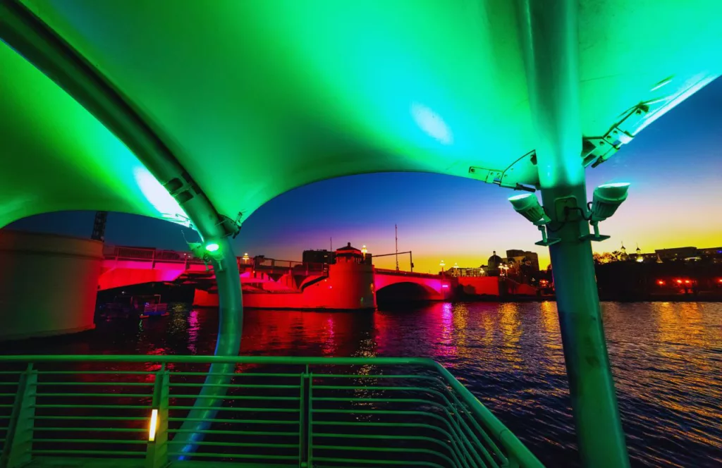 Tampa Riverwalk at the holidays, glowing in colorful, vibrant lights reflecting off the water. Keep reading to find out more about the best hotels near Busch Gardens, Tampa.