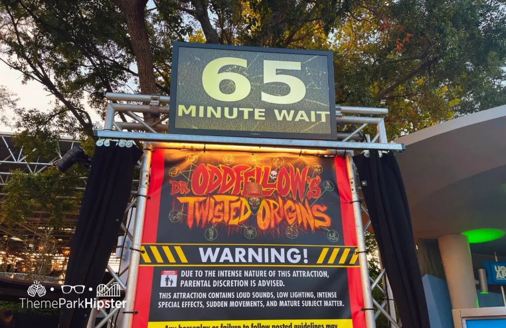 65 minute wait sign at Oddfellow Twisted Origin House at the 2023 Halloween Horror Nights HHN 32 Universal Studios Orlando. Keep reading to discover more about Halloween Horror Nights Stay and Scream.