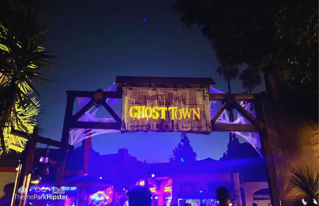 Ghost Town Scare Zone wooden antique looking sign with cobwebs at 2023 Knott's Scary Farm at Knott's Berry Farm in California. Keep reading to find out more about Knott’s Scary Farm houses.