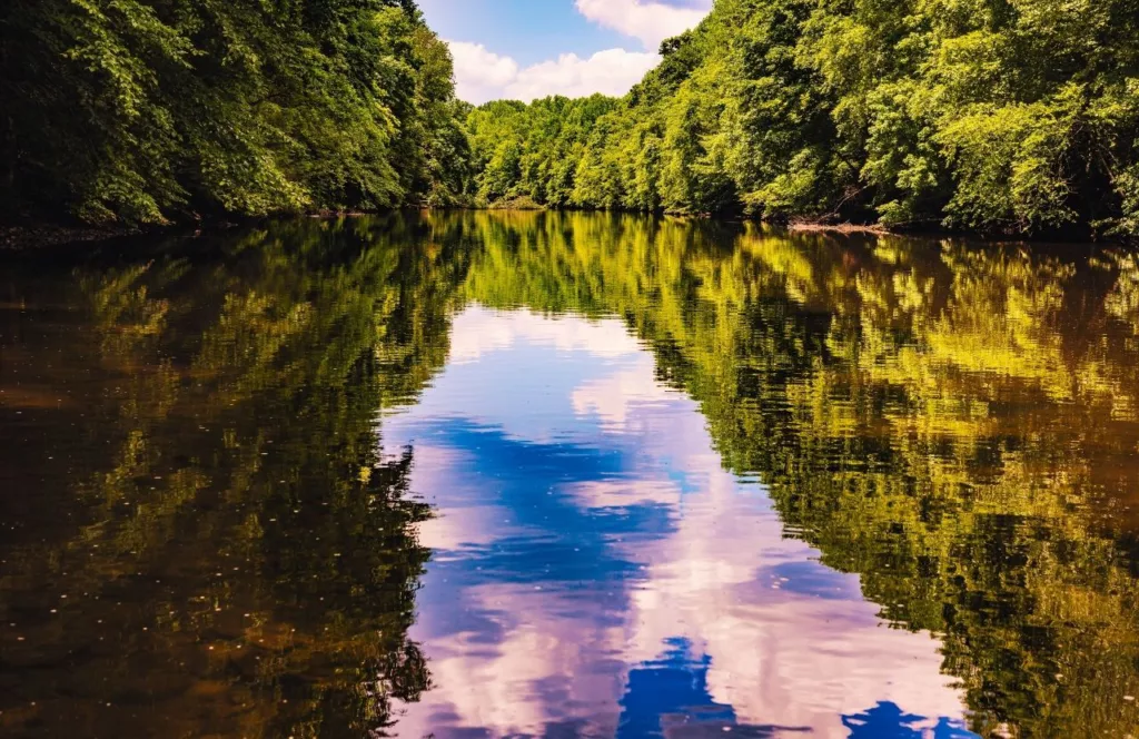 Swatara Creek Park with the colors of the purple and blue sky reflecting in the water as well as the trees lining the banks. Keep reading to find out more about the top 10 best things to do around Hersheypark.