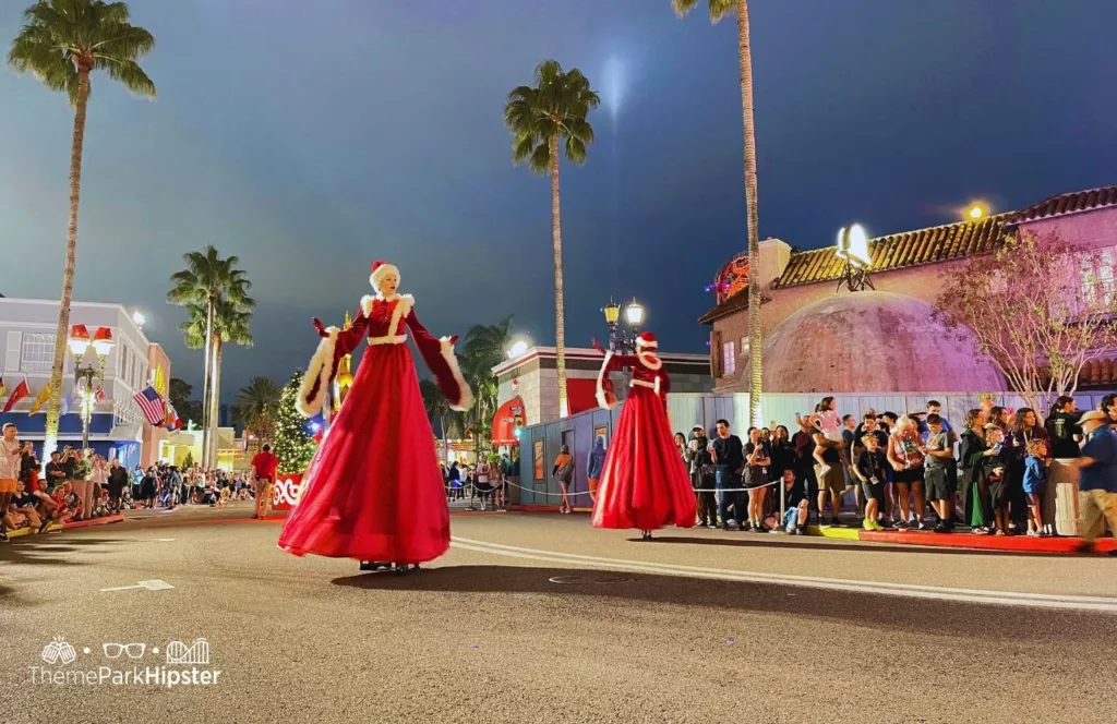 Christmas at Universal Orlando Holiday Parade featuring Macy's dancing ladies in red Christmas gowns. Keep reading to discover more about Universal Studios Holiday Parade.