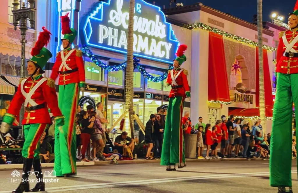 Christmas at Universal Orlando Holiday Parade featuring Macy's featureing toy soldiers in green and red on stilts. Keep reading to find out more about the Christmas parade at Universal Studios Florida.