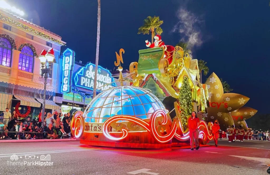 Christmas at Universal Orlando Holiday Parade featuring Macy's float with Santa Claus in his sleigh above snow capped rooftops.Keep reading to discover more about Universal Studios Holiday Parade.