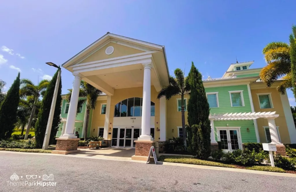 Encore Resort at Reunion grand home office in yellow white and green with towering trees and shuttle pick up and drop area. Keep reading to learn more about Encore Resort.  