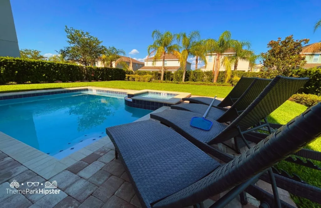 Pool area with lounge chairs and large green grassy backyard at a  5 Bedroom villa at Encore Resort at Reunion. Keep reading to learn more about Encore Resort Orlando.