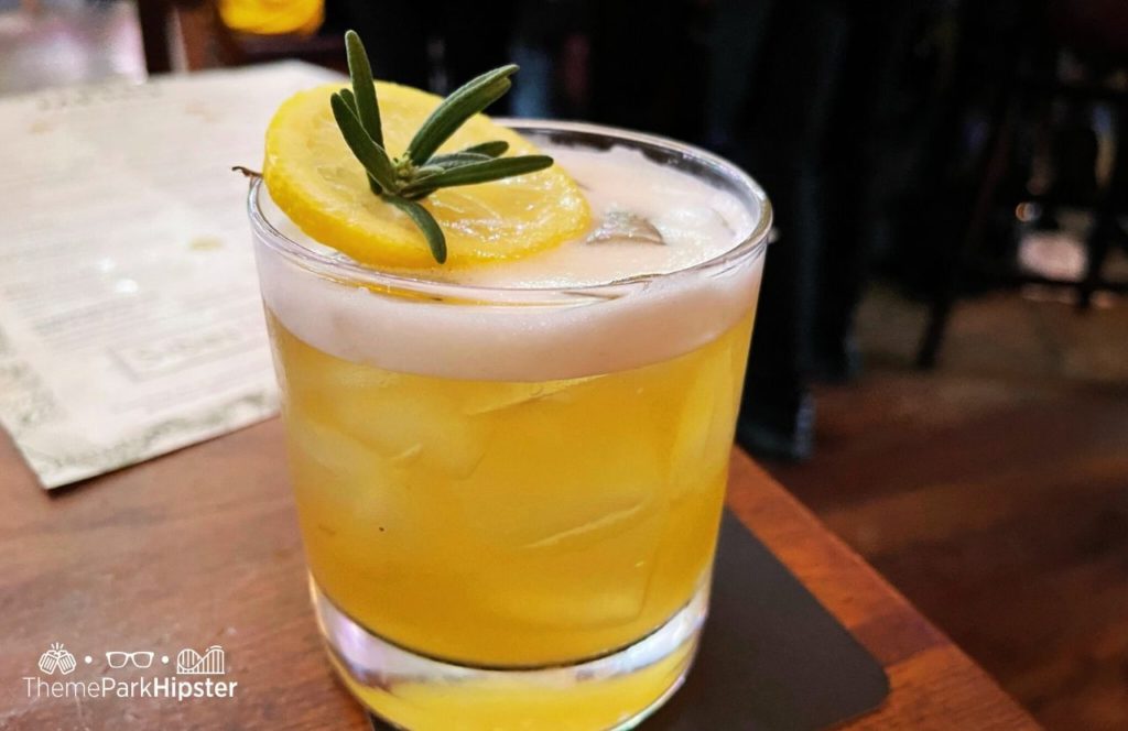 Walt Disney World Disney Springs Raglan Road Restaurant Rosemary and Maple Whiskey Sour Drink Cocktail. One of the best drinks at Disney Springs and the best adult beverages at Walt Disney World!
