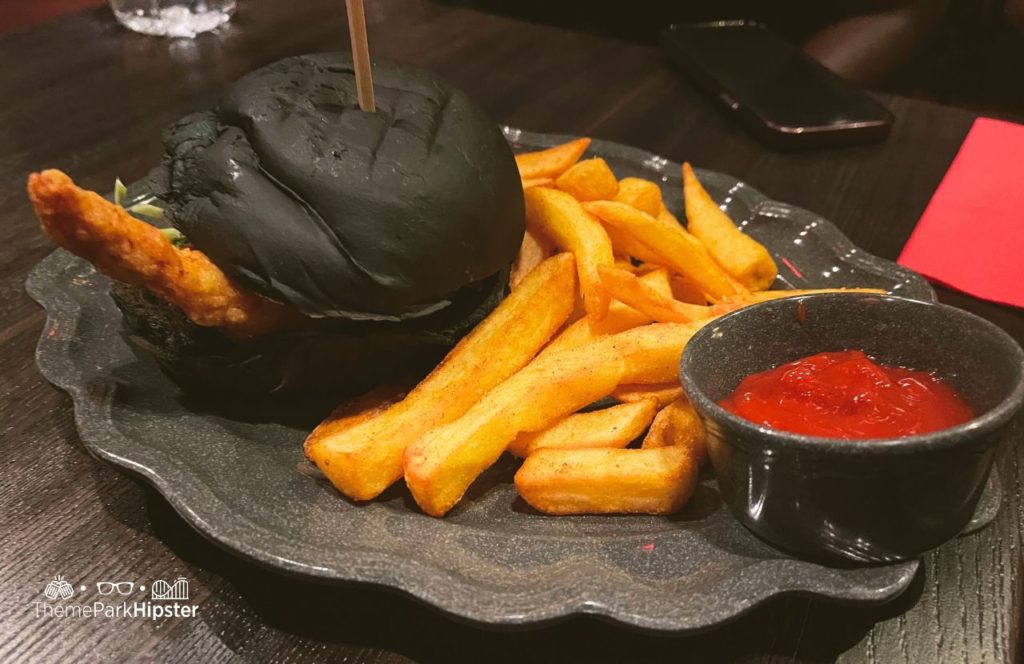 Dark Universe Das Stakehaus Restaurant Blood Orange Chicken Sandwich with Fries Universal Epic Universe Theme Park Orlando
