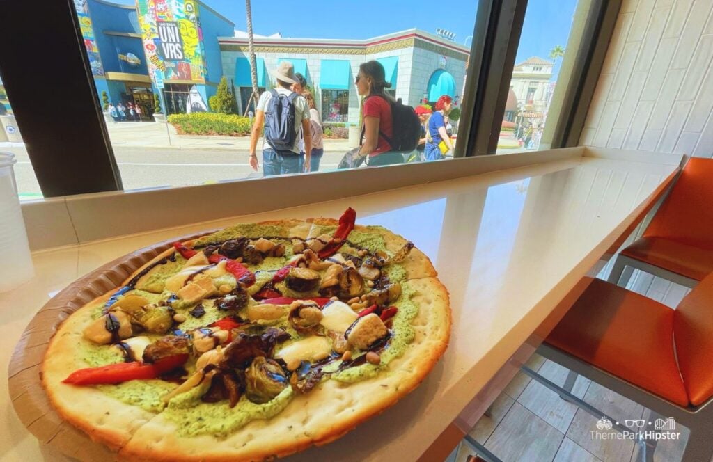 TODAY Cafe Restaurant in Universal Studios Florida Chicken Pesto Flatbread Pizza Food with cauliflower crust, pesto ricotta, grilled chicken, brussels sprouts, red peppers, mozzarella, pine nuts, and a balsamic glaze.
