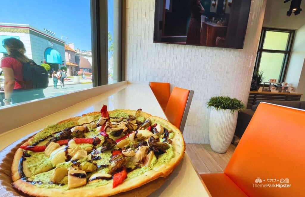 TODAY Cafe Restaurant in Universal Studios Florida Chicken Pesto Flatbread Pizza Food with cauliflower crust, pesto ricotta, grilled chicken, brussels sprouts, red peppers, mozzarella, pine nuts, and a balsamic glaze.